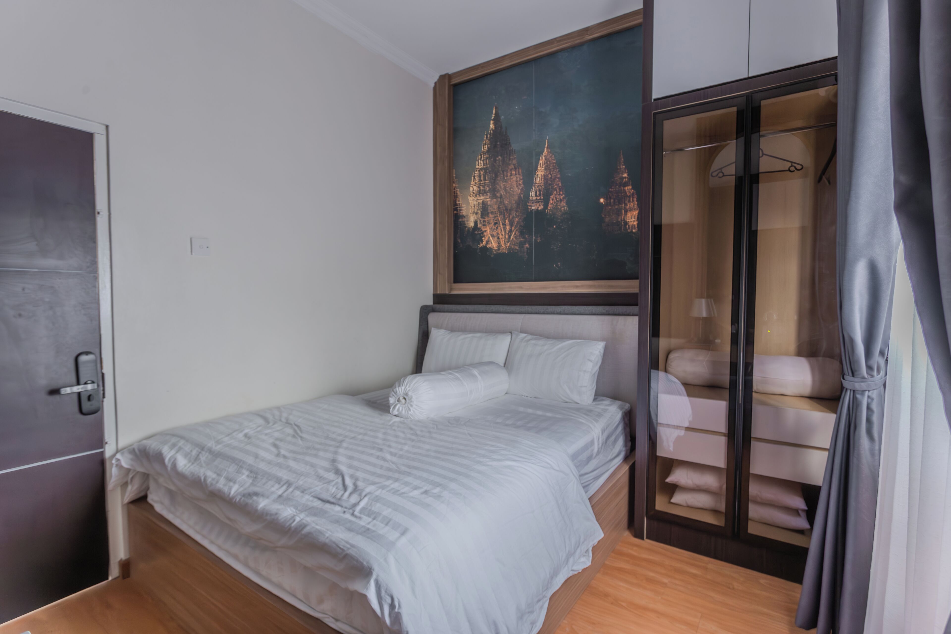 Ein Schlafzimmer mit einem Bett, einem Kleiderschrank und einem Gemälde eines Tempels an der Wand.