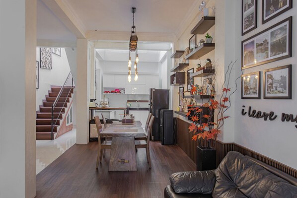 A modern kitchen with a dining area, a staircase, and a living room with a leather sofa. - INEZ Homestay (Yogyakarta)