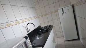 Een keuken met witte kasten, een gasfornuis, een magnetron en een koelkast.