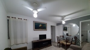 Een woonkamer met een televisie, bank en een eethoek.