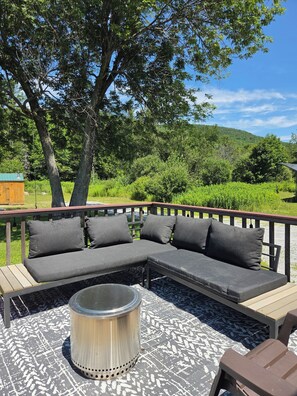 A wooden deck with a sectional sofa and a metal table. - Cozy 3-bedroom house minutes to Okemo and downtown Ludlow (Mount Holly)