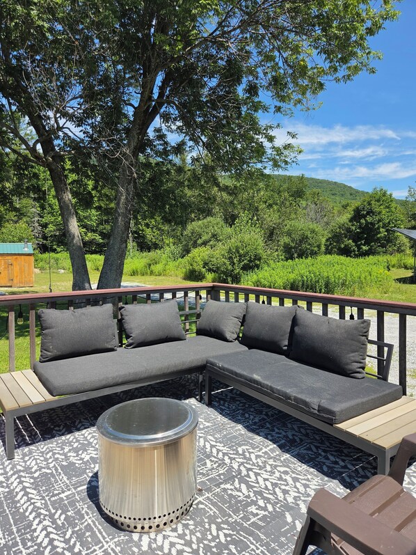 Een houten terras met een modulaire bank en een metalen tafel.