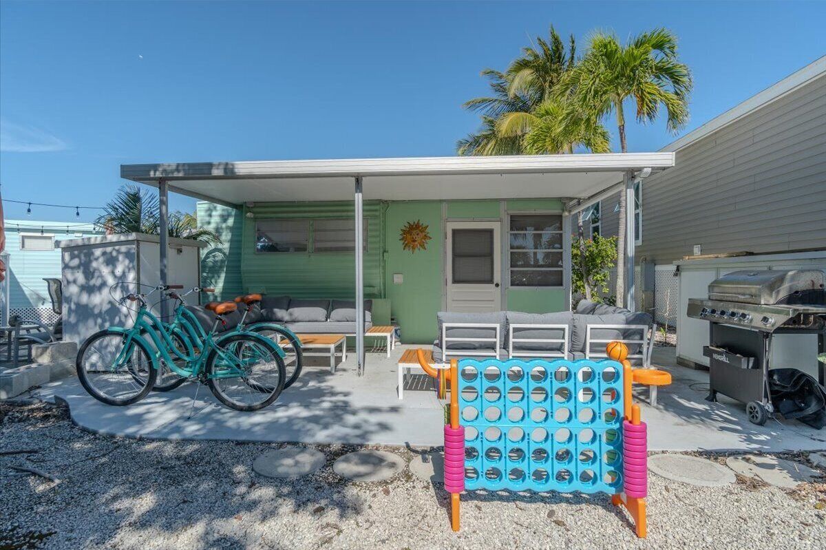 A single-story house with a covered porch, a grill, and a bicycle.