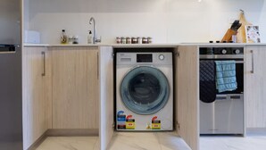 A compact kitchen with a built-in washer and dryer, a sink, and a stove. - Cozy Studio Escape in Wilmer (Christchurch)