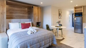 A modern hotel room with a large bed, a dining table, and a kitchen area. - Cozy Studio Escape in Wilmer (Christchurch)