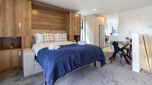 Quarto moderno com cama, mesas de cabeceira e um espaço de trabalho.