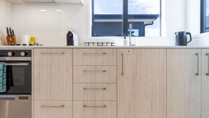 Cozinha moderna com armários de madeira clara, eletrodomésticos de aço inoxidável e uma janela ampla que oferece iluminação natural.