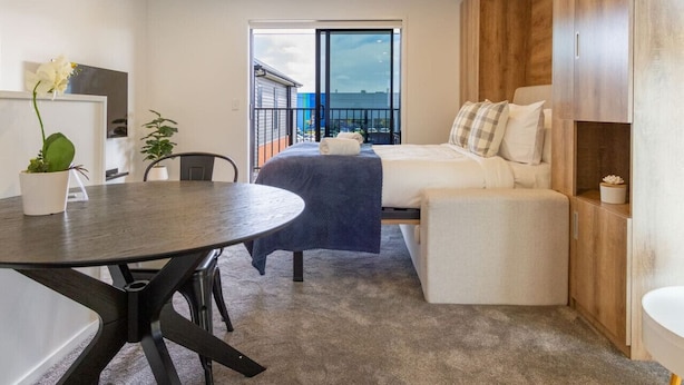 Quarto moderno com cama, mesa de cabeceira e varanda com vista.