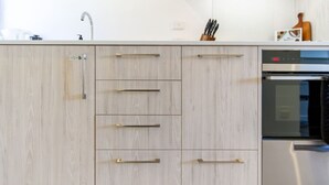 A modern kitchen with light wood cabinetry, stainless steel appliances, and a minimalist design.