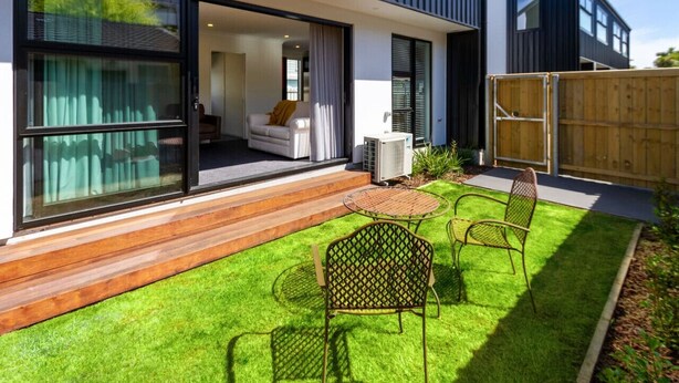 Ein modernes Haus mit einer Terrasse, ausgestattet mit einem Holzboden, einem kleinen runden Tisch und zwei Metallstühlen.