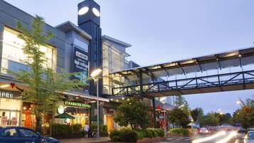A modern building with a Starbucks coffee shop, a pedestrian bridge, and a parking lot with cars.