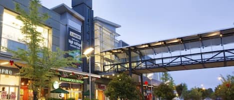 A modern building with a Starbucks coffee shop, a pedestrian bridge, and a parking lot with cars.