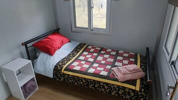 Cozy retreat with a single bed, storage unit, and window.