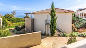 Ein modernes Gebäude mit einem Ziegeldach, einem kleinen Balkon und Blick aufs Meer.
