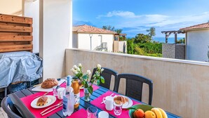 Ein Balkon mit einem Frühstückstisch, komplett mit Croissants, einer Wasserflasche und einem Glas Saft.