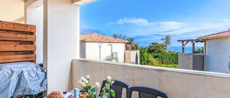 A balcony with a table set for breakfast, including croissants, a bottle of water, and a glass of juice.