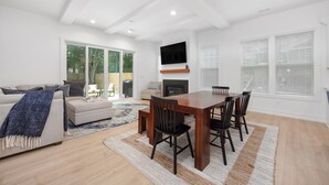 A modern living room with a sofa, coffee table, and dining table. - Sleeps 10. Near NODA, Plaza, Uptown. Pet Friendly. Fenced Yard + Firepit (Charlotte)