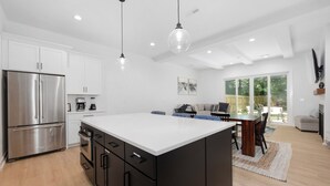A modern kitchen with a central island, stainless steel appliances, and pendant lighting. - Sleeps 10. Near NODA, Plaza, Uptown. Pet Friendly. Fenced Yard + Firepit (Charlotte)