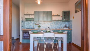 Une cuisine compacte avec un coin repas, dotée d’un plan de travail carrelé, de meubles en bois et d’un îlot central avec des chaises.
