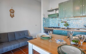 Una cocina moderna con baldosas de mosaico azules, una mesa de comedor de madera y un sofá gris.