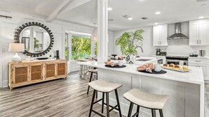 A modern kitchen with a central island, white cabinetry, and a large mirror above the sink.