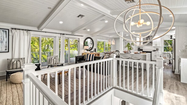 A spacious living area with a white railing, a dining area, and a kitchen with white cabinets.