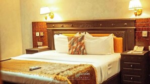Ein Hotelzimmer mit einem hölzernen Kopfteil, zwei Nachttischlampen, einem Bett mit weißen Bettwäsche und einem Telefon auf dem Nachttisch.