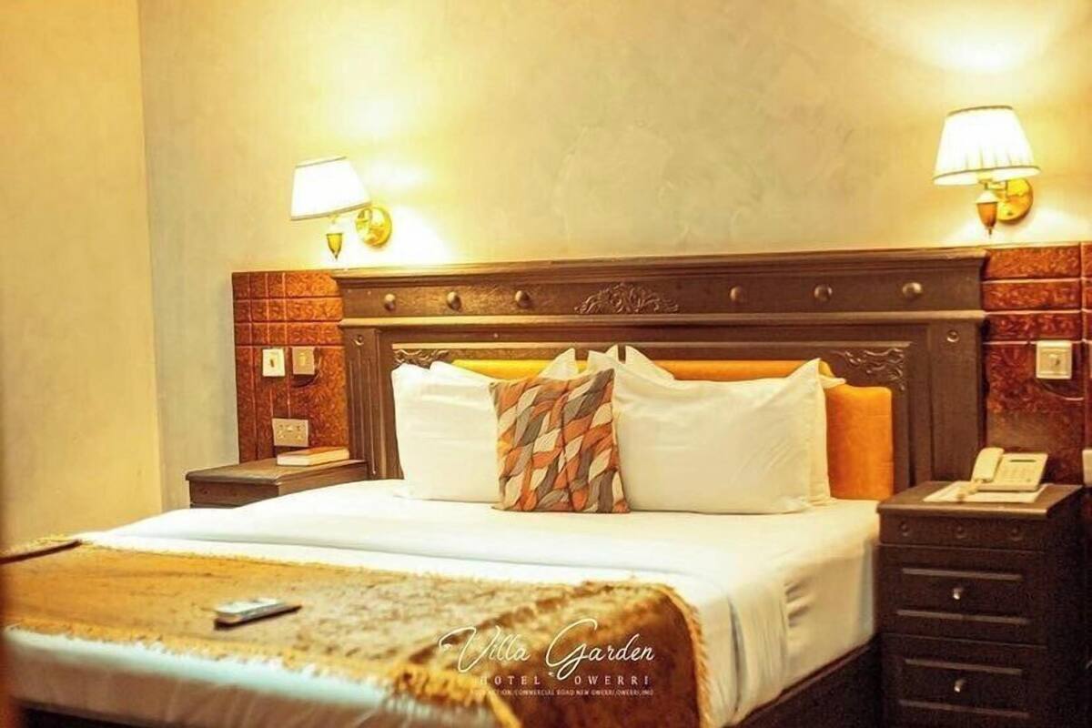 A hotel room with a wooden headboard, two bedside lamps, a bed with white linens, and a telephone on the nightstand.