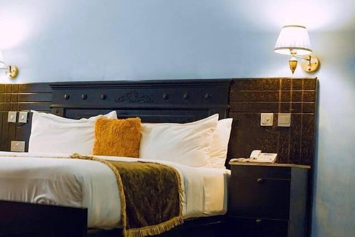 A hotel room with a bed, a nightstand, and a lamp.