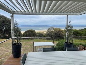 Un espace extérieur abrité, aménagé avec des sièges, et offrant une vue sur la plage et l’océan.