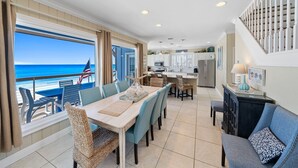A spacious kitchen with a view of the ocean, a dining area with a view, and a staircase leading to a balcony. - Private Beach | Exclusive 4BR Dune Allen (Santa Rosa Beach)