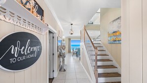 A hallway with a 'Welcome to our home' sign, a staircase, and a view of the ocean. - Private Beach | Exclusive 4BR Dune Allen (Santa Rosa Beach)