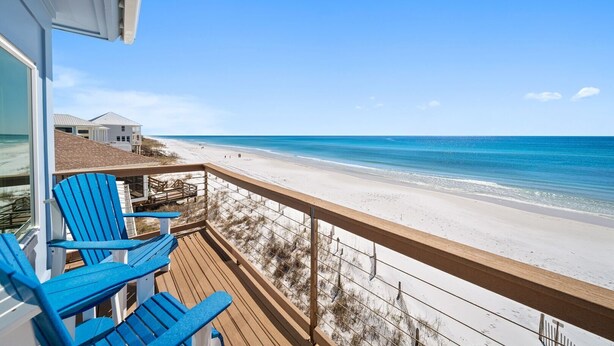 A balcony with blue Adirondack chairs overlooking a beach with clear blue water and a sandy shore. - Private Beach | Exclusive 4BR Dune Allen (Santa Rosa Beach)