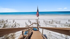 A wooden boardwalk leading to a beach with an American flag. - Private Beach | Exclusive 4BR Dune Allen (Santa Rosa Beach)