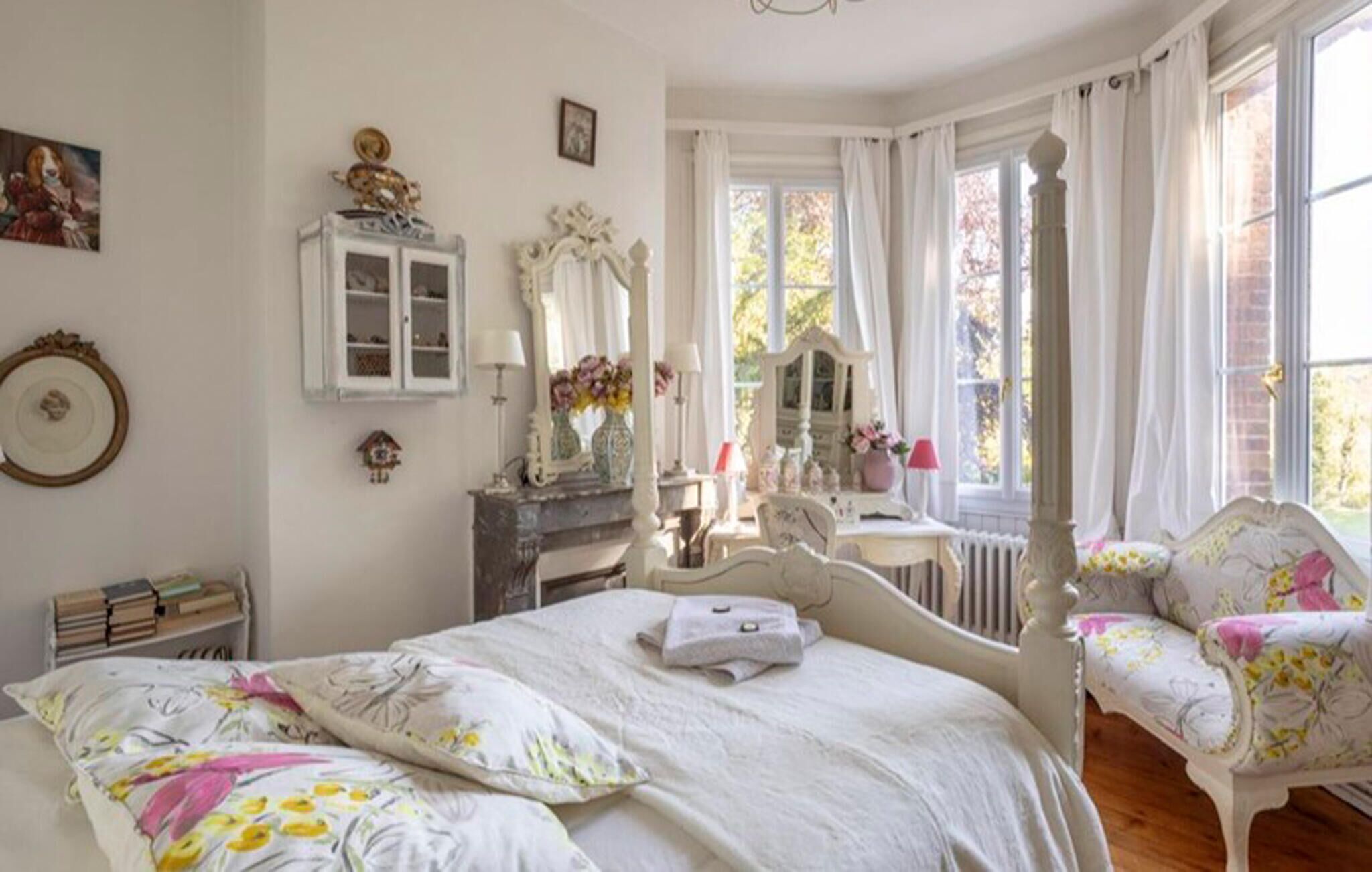 Ett sovrum med en stor säng, en byrå, en sminkbord och en stol med blommigt tyg.
