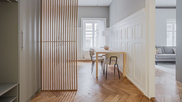 Een modern interieur met een eethoek, houten vloer en uitzicht op de aangrenzende zithoek.