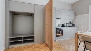 Een moderne keuken met witte kasten, een houten vloer en een eethoek met een tafel en stoelen.