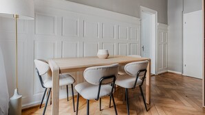 Een eethoek met een houten tafel, vier stoelen, een witte deur en een lamp.