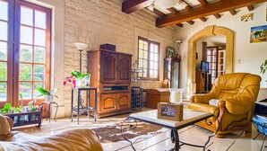 Un salon spacieux avec une grande fenêtre, des meubles en bois et un fauteuil en cuir.