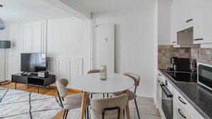 A modern kitchen with white cabinets, a dining table with four chairs, a TV, and a coffee maker. - Blueground | Oberstrass, rooftop, a/c, equipped (Zurich)