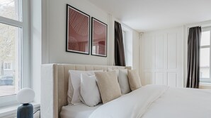 A hotel room with a large bed, a bedside table with a lamp, and a window with curtains. - Blueground | Oberstrass, rooftop, a/c, equipped (Zurich)