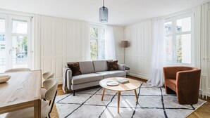 Ein modernes Wohnzimmer mit einem grauen Sofa, einem runden Couchtisch und einem braunen Sessel.