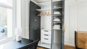 Ein moderner Kleiderschrank mit offenen Türen, weißen Schubladen und Platz zum Aufhängen.