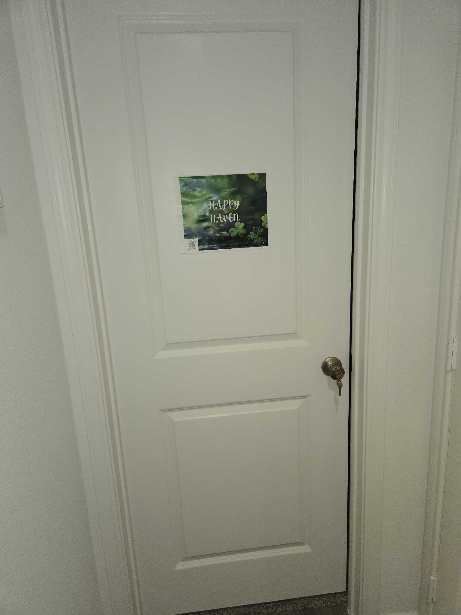 A white door with a poster that reads "Happy Hanen" and cloverleaf symbols.