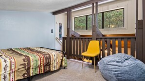 Een slaapkamer met een bed, een gele stoel en een relaxfauteuil.