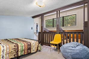 A bedroom with a bed, a yellow chair, and a bean bag chair. - Snug 2-Bedroom Condo- Walking Distance to Ski Lift (Angel Fire)
