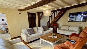 A living room with two sofas, a coffee table, and a TV mounted on the wall. - Chouette and Hibou 30pers 2 Cottage : jacuzzi (Quibou)