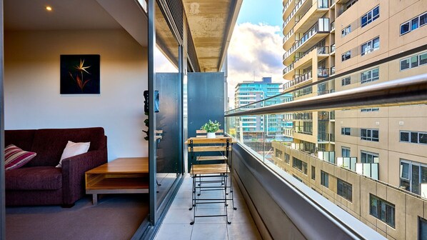 A modern apartment with a balcony, a sofa, a small table, and a potted plant.