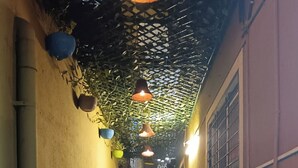 A narrow corridor with a checkered floor, potted plants, hanging lights, and a window on the right. - Komfort Inn (Pune)