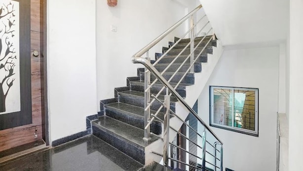 A staircase with a metal handrail and a window with bars. - Komfort Inn (Pune)